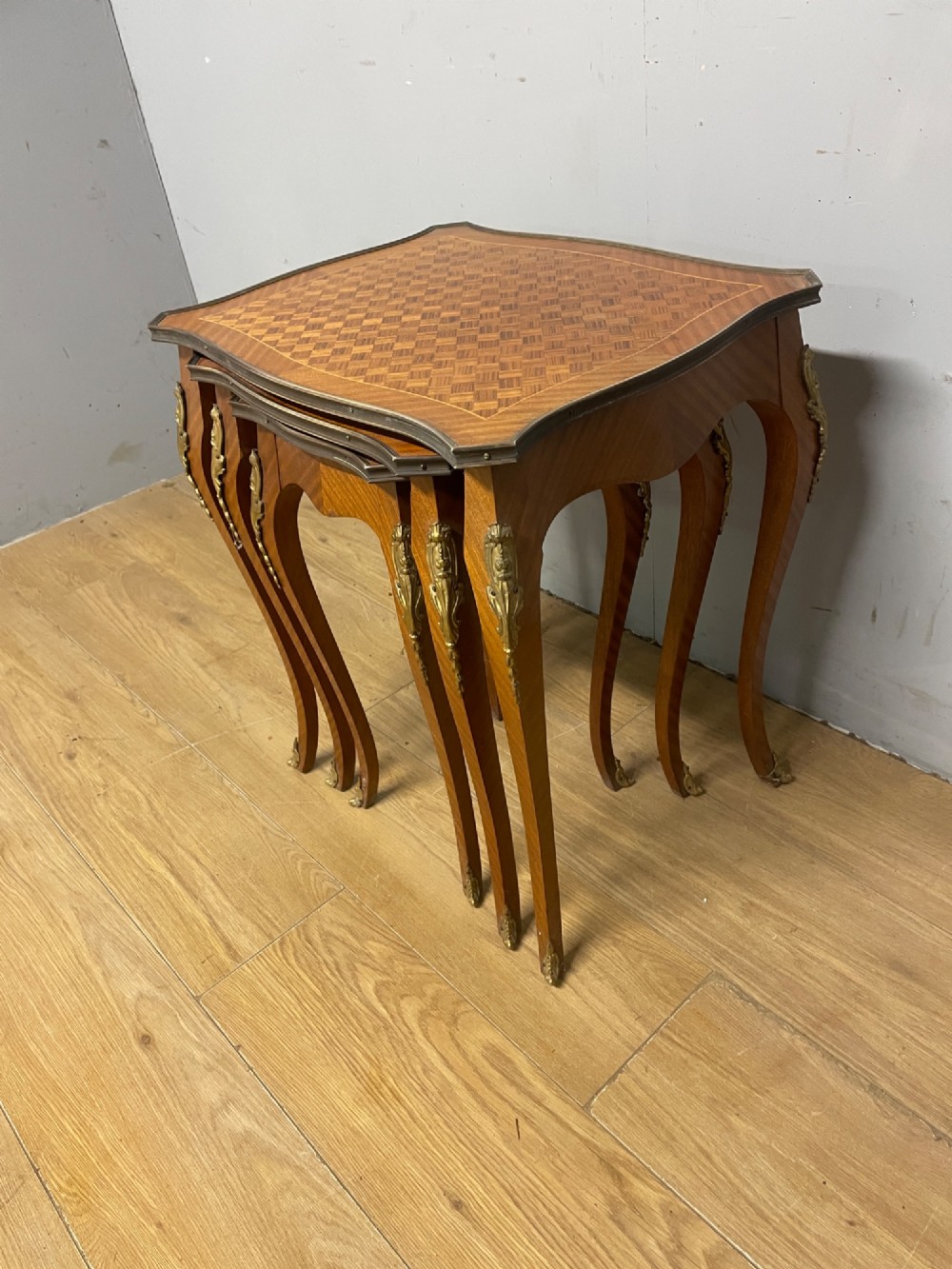 A set of three graduated French kingwood nesting tables featuring parquetry inlaid tops, cabriole legs, and gilded ormolu mounts. View V