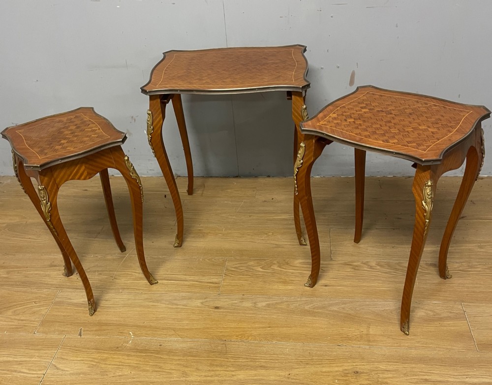 A set of three graduated French kingwood nesting tables featuring parquetry inlaid tops, cabriole legs, and gilded ormolu mounts. View VI