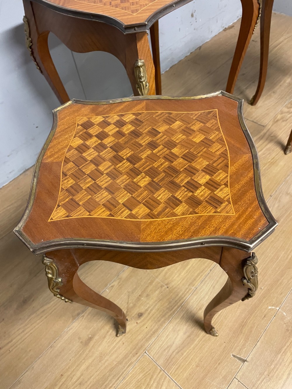 A set of three graduated French kingwood nesting tables featuring parquetry inlaid tops, cabriole legs, and gilded ormolu mounts. View VII
