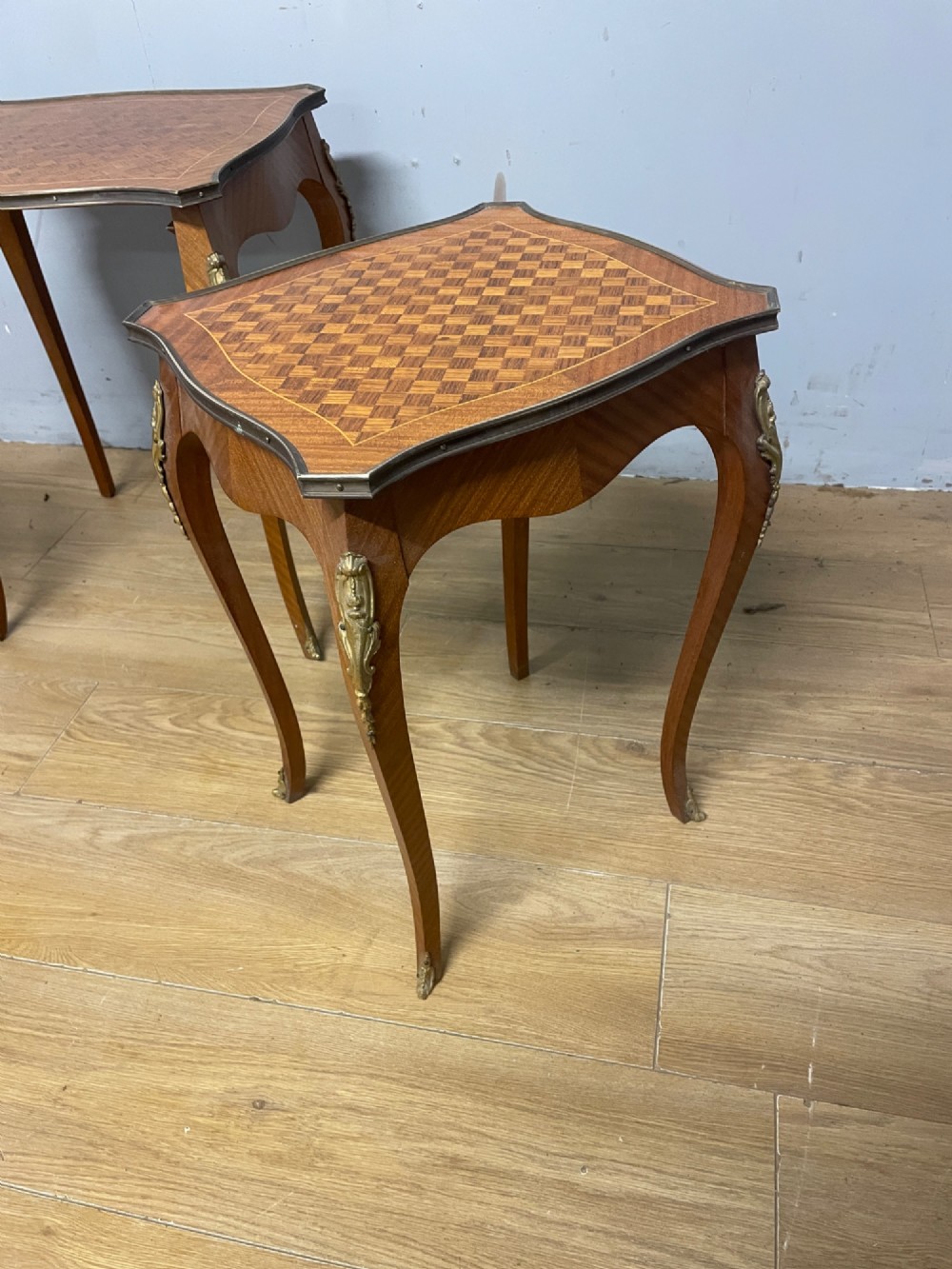 A set of three graduated French kingwood nesting tables featuring parquetry inlaid tops, cabriole legs, and gilded ormolu mounts. View X