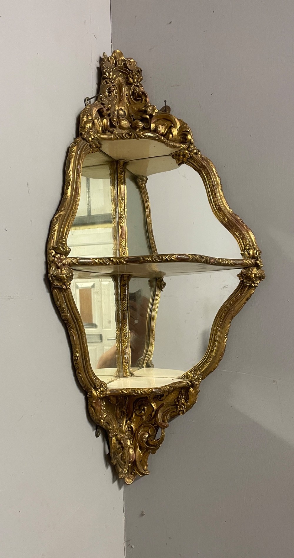 A 19th-century carved giltwood corner wall bracket featuring Rococo scrolling foliage, mirrored back plates, and tiered display shelves. View III