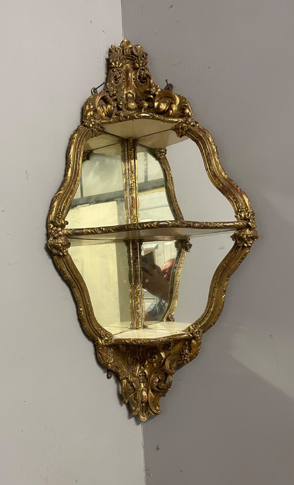 A 19th-century carved giltwood corner wall bracket featuring Rococo scrolling foliage, mirrored back plates, and tiered display shelves. View IV