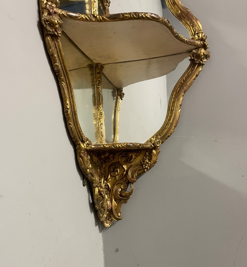 A 19th-century carved giltwood corner wall bracket featuring Rococo scrolling foliage, mirrored back plates, and tiered display shelves. View V