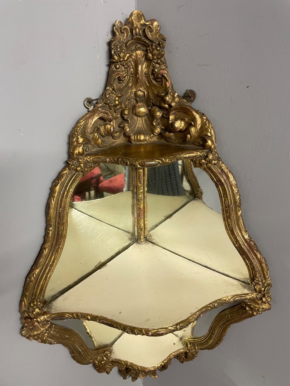 A 19th-century carved giltwood corner wall bracket featuring Rococo scrolling foliage, mirrored back plates, and tiered display shelves. View VI