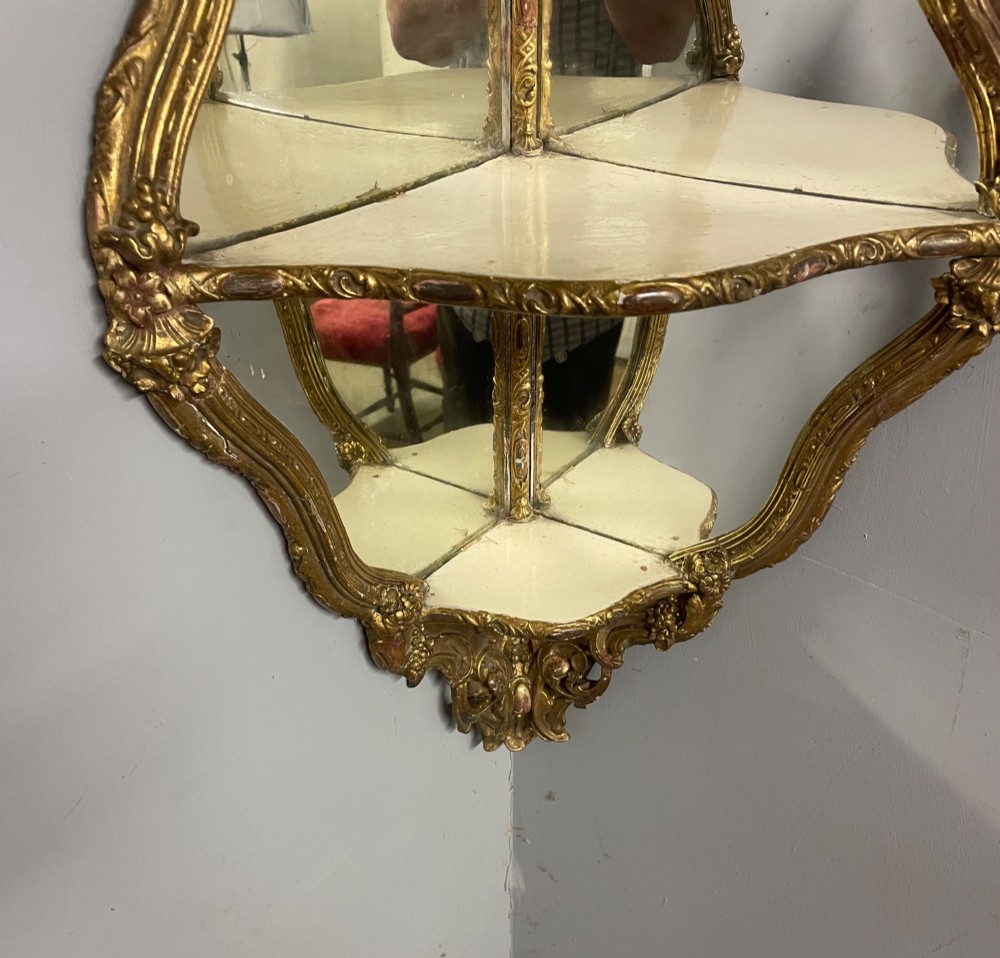A 19th-century carved giltwood corner wall bracket featuring Rococo scrolling foliage, mirrored back plates, and tiered display shelves. View VII
