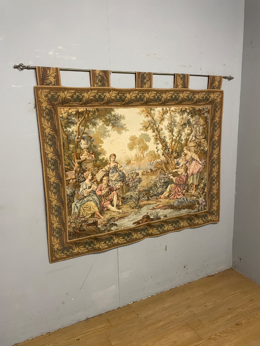 A large woven wall tapestry depicting figures in an 18th-century pastoral landscape with trees, classical sculpture, and a leaf pattern border. View II