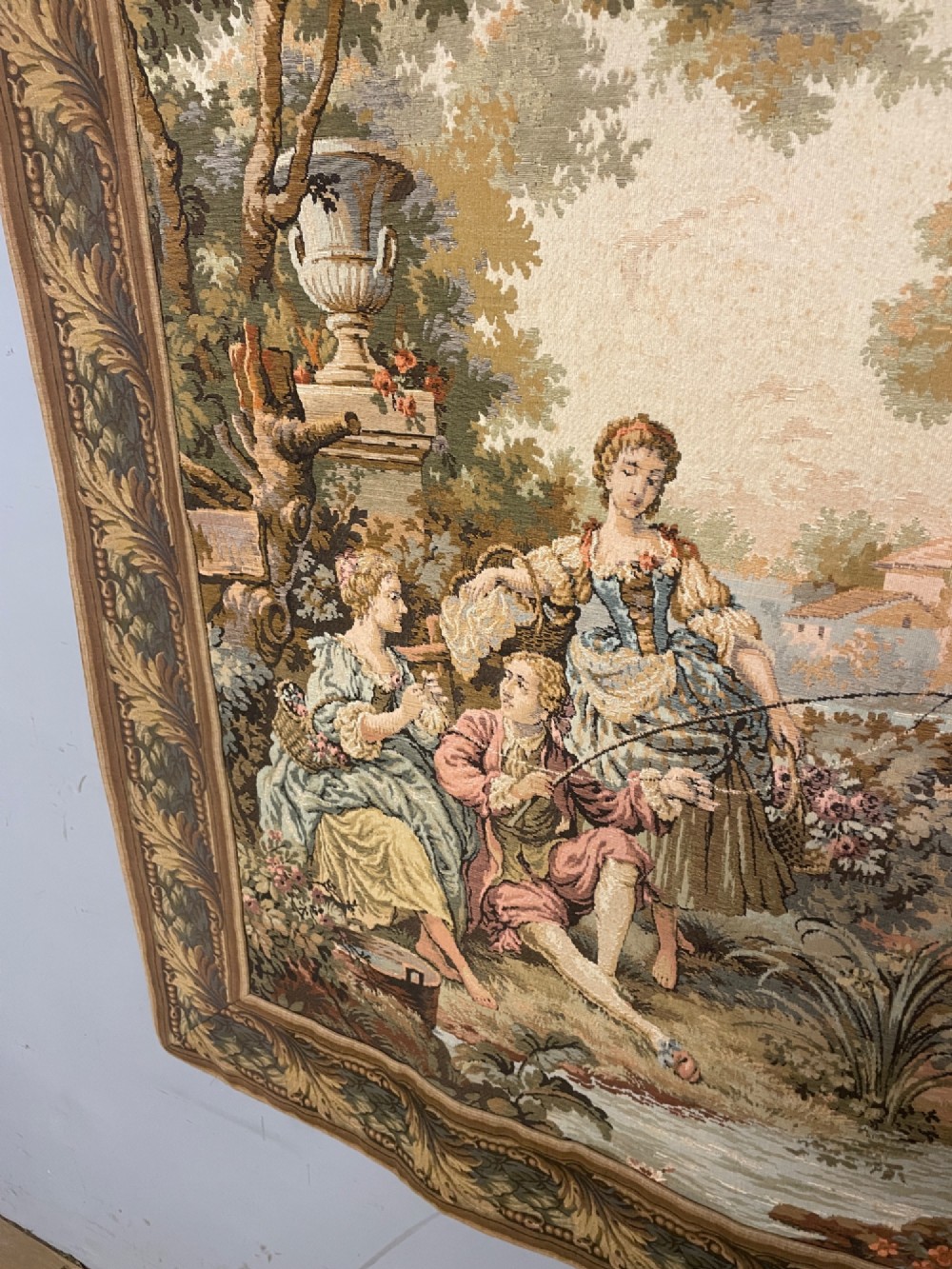 A large woven wall tapestry depicting figures in an 18th-century pastoral landscape with trees, classical sculpture, and a leaf pattern border. View IV