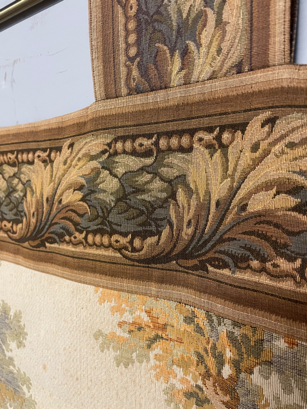A large woven wall tapestry depicting figures in an 18th-century pastoral landscape with trees, classical sculpture, and a leaf pattern border. View VI
