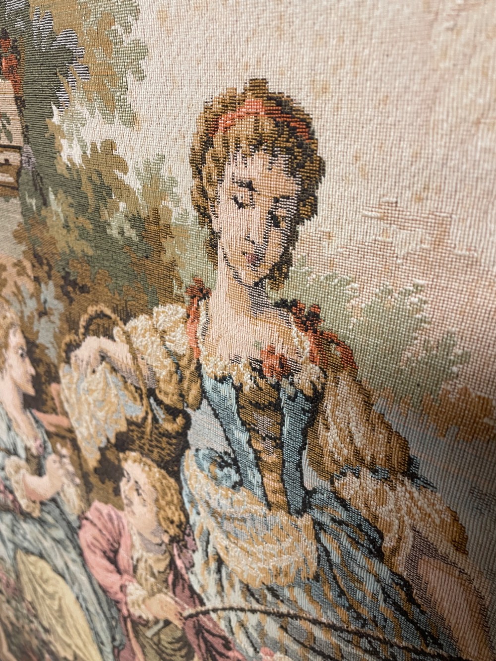 A large woven wall tapestry depicting figures in an 18th-century pastoral landscape with trees, classical sculpture, and a leaf pattern border. View VII