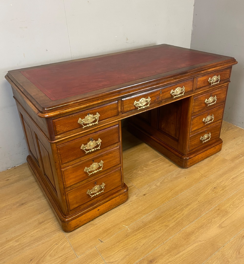 A 19th-century walnut twin pedestal desk featuring a red leather writing insert and brass drop handles.
