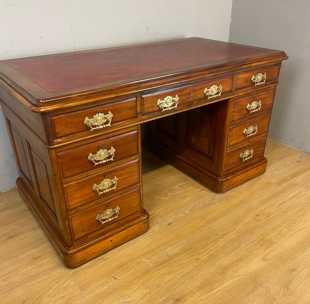 A 19th-century walnut twin pedestal desk featuring a red leather writing insert and brass drop handles. View IV