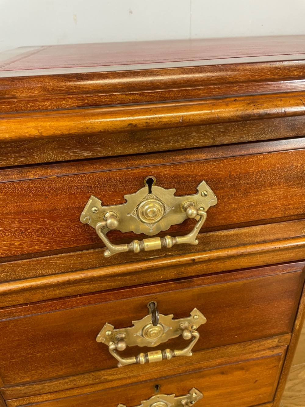 A 19th-century walnut twin pedestal desk featuring a red leather writing insert and brass drop handles. View V