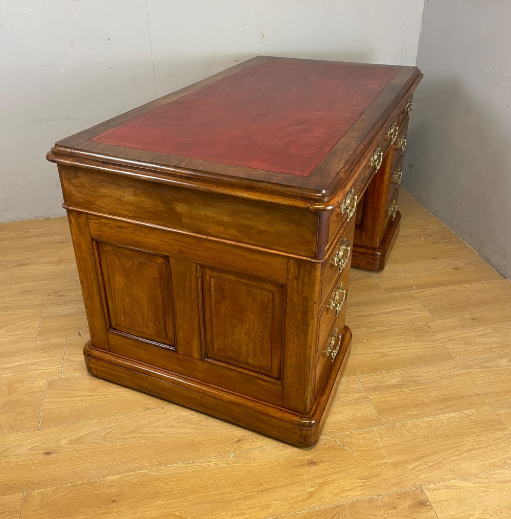 A 19th-century walnut twin pedestal desk featuring a red leather writing insert and brass drop handles. View VI