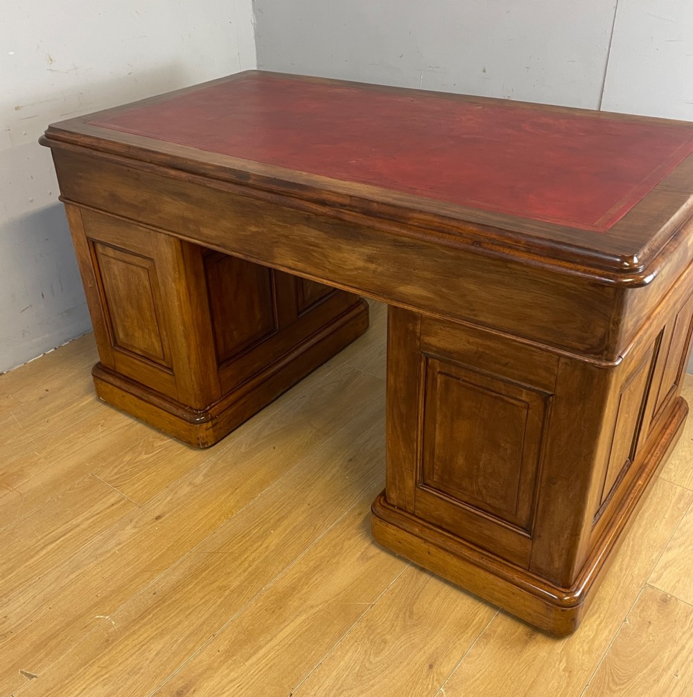 A 19th-century walnut twin pedestal desk featuring a red leather writing insert and brass drop handles. View VII