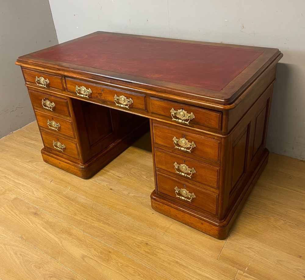 A 19th-century walnut twin pedestal desk featuring a red leather writing insert and brass drop handles. View X