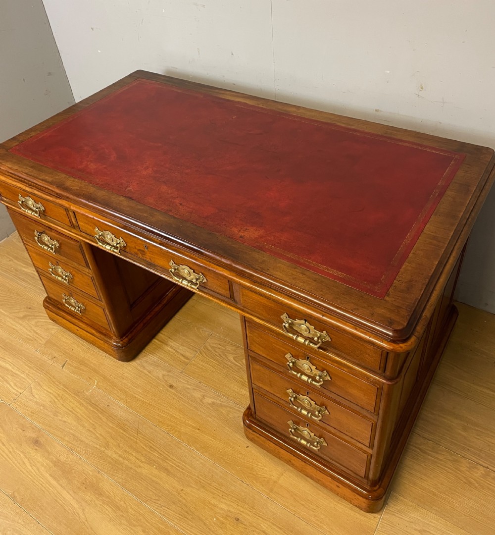 A 19th-century walnut twin pedestal desk featuring a red leather writing insert and brass drop handles. View XI