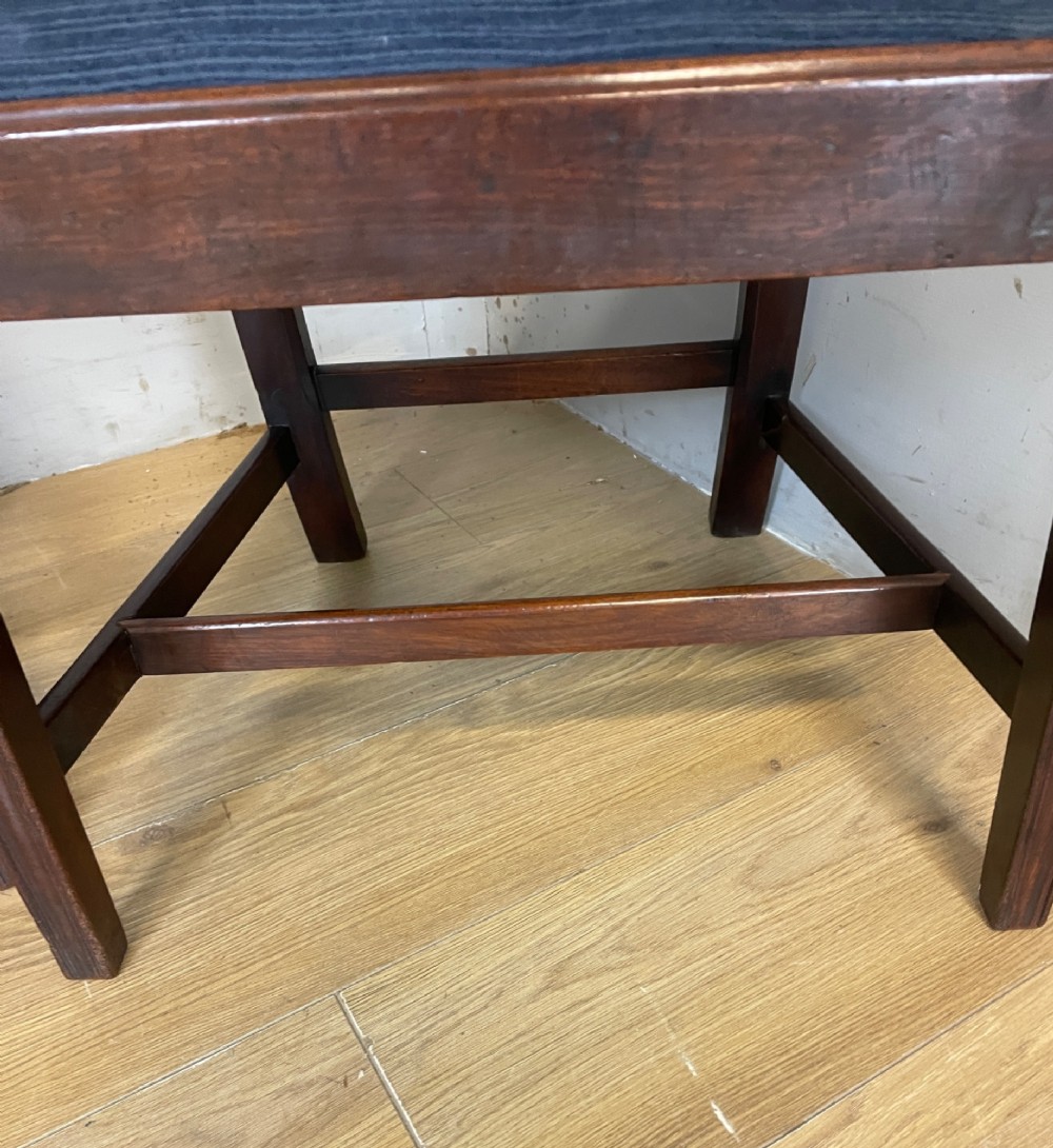 A set of four antique mahogany Chippendale style dining chairs with decorative pierced back splats and dark upholstered seats arranged side by side. View IV