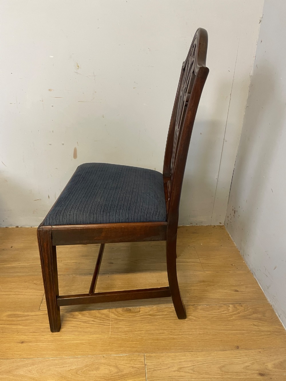 A set of four antique mahogany Chippendale style dining chairs with decorative pierced back splats and dark upholstered seats arranged side by side. View VII