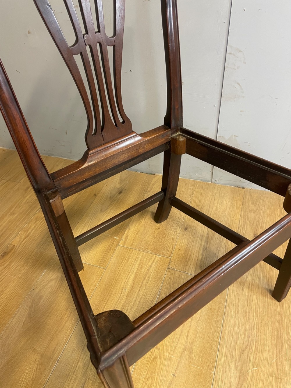 A set of four antique mahogany Chippendale style dining chairs with decorative pierced back splats and dark upholstered seats arranged side by side. View X