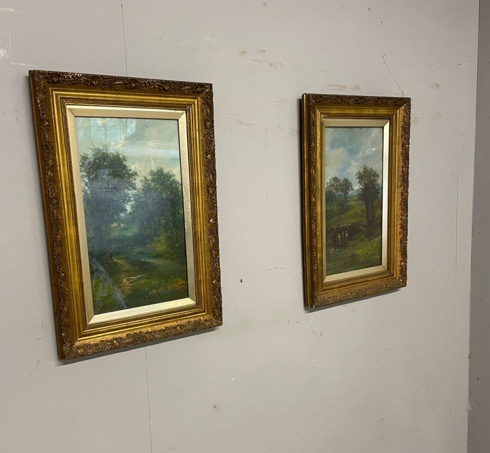 A pair of vertical late 19th-century oil paintings depicting green river and woodland landscapes in ornate gilded frames. View IV