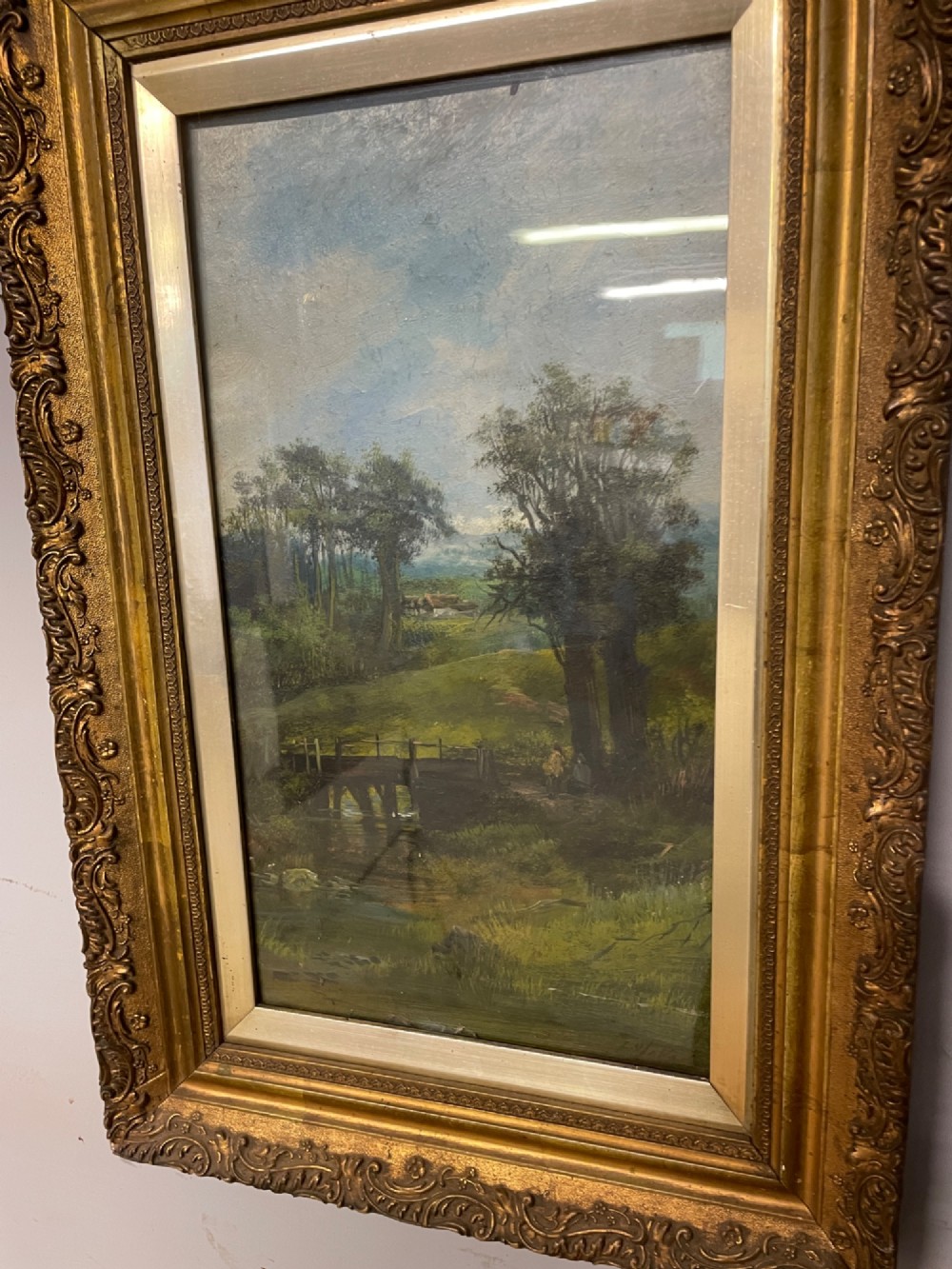 A pair of vertical late 19th-century oil paintings depicting green river and woodland landscapes in ornate gilded frames. View VI