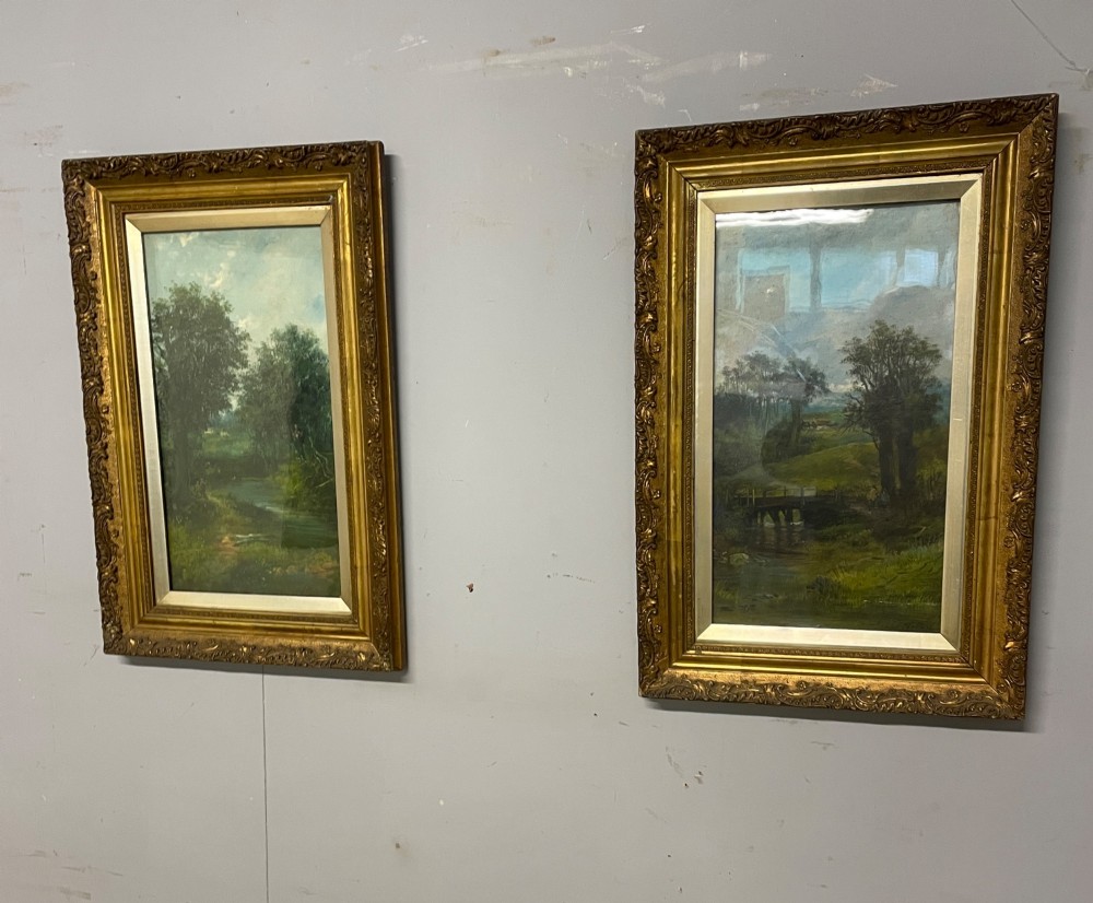 A pair of vertical late 19th-century oil paintings depicting green river and woodland landscapes in ornate gilded frames. View VII