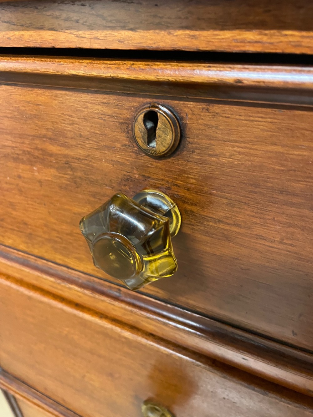 A nineteenth-century solid teak chest of drawers featuring two short drawers over two long drawers, fitted with faceted glass knobs and resting on turned bun feet. View VI