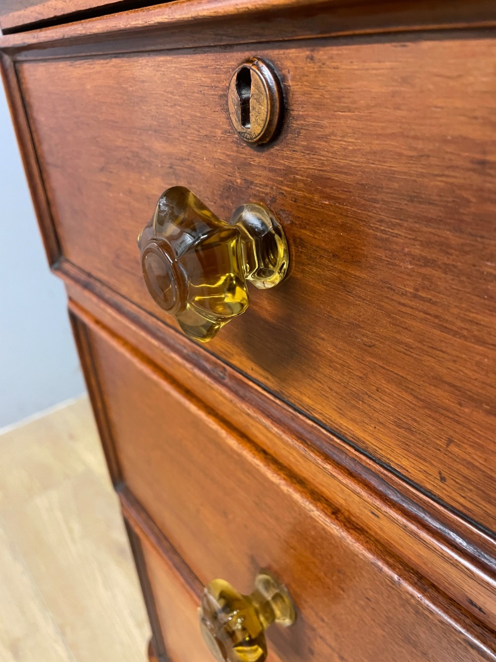 A nineteenth-century solid teak chest of drawers featuring two short drawers over two long drawers, fitted with faceted glass knobs and resting on turned bun feet. View VII