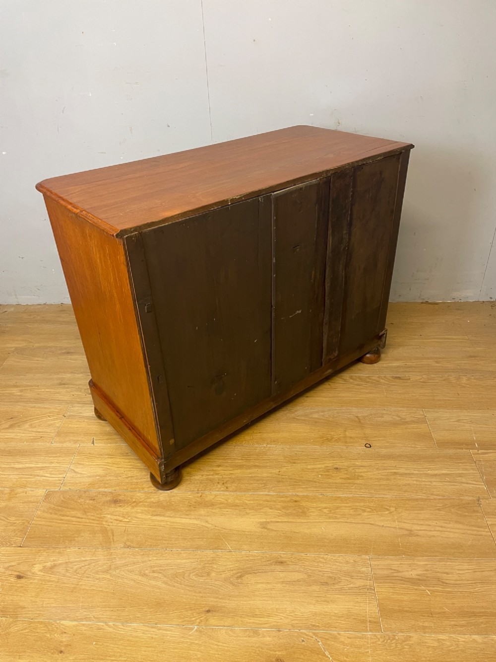 A nineteenth-century solid teak chest of drawers featuring two short drawers over two long drawers, fitted with faceted glass knobs and resting on turned bun feet. View XIII