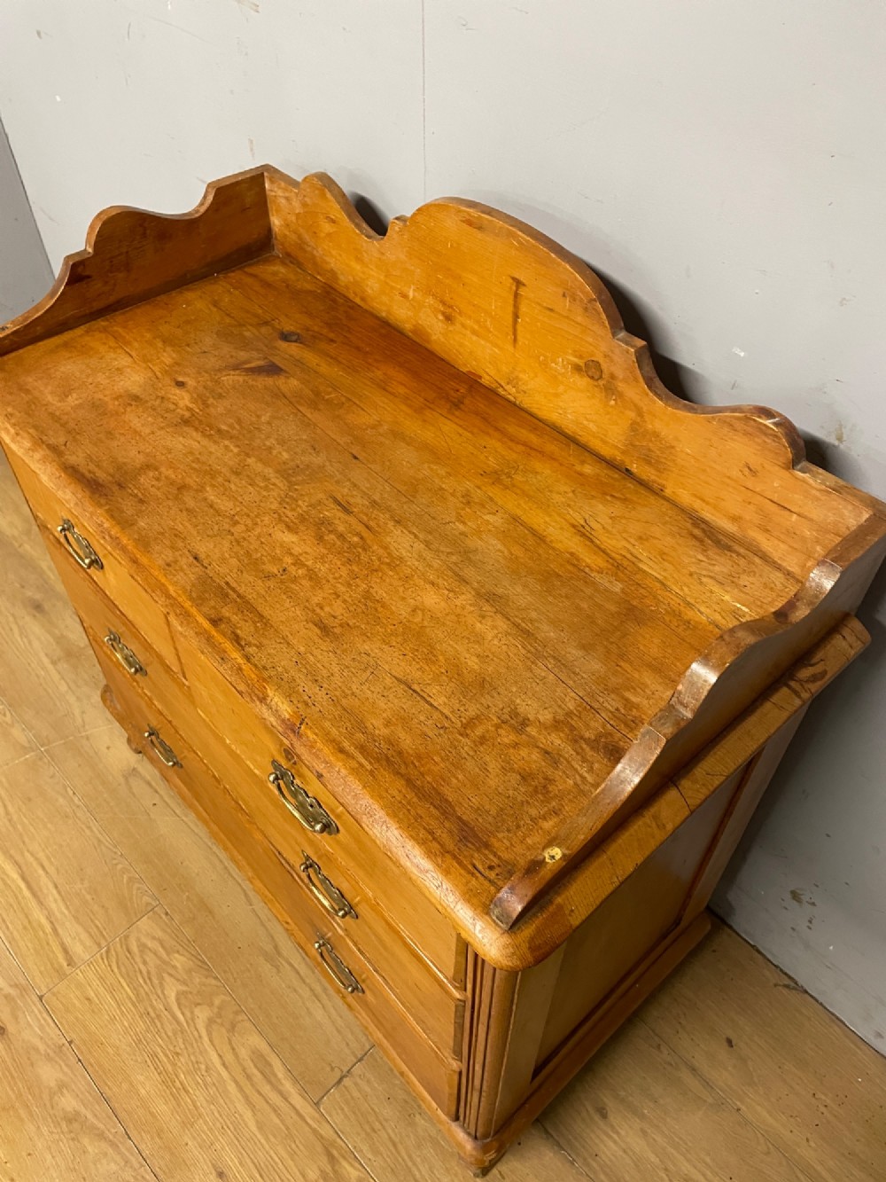 A nineteenth-century warm pine chest of drawers featuring a shaped gallery back, two short over two long drawers, and brass handles. View VII
