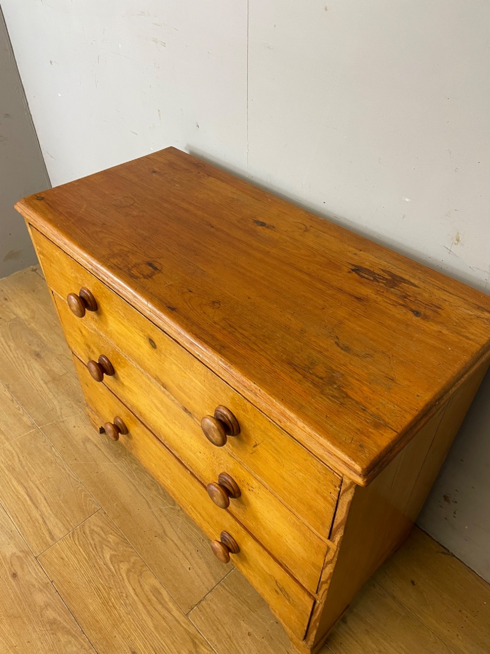 A nineteenth-century pine chest of drawers featuring three full-width drawers with turned wooden handles and bracket feet. View III