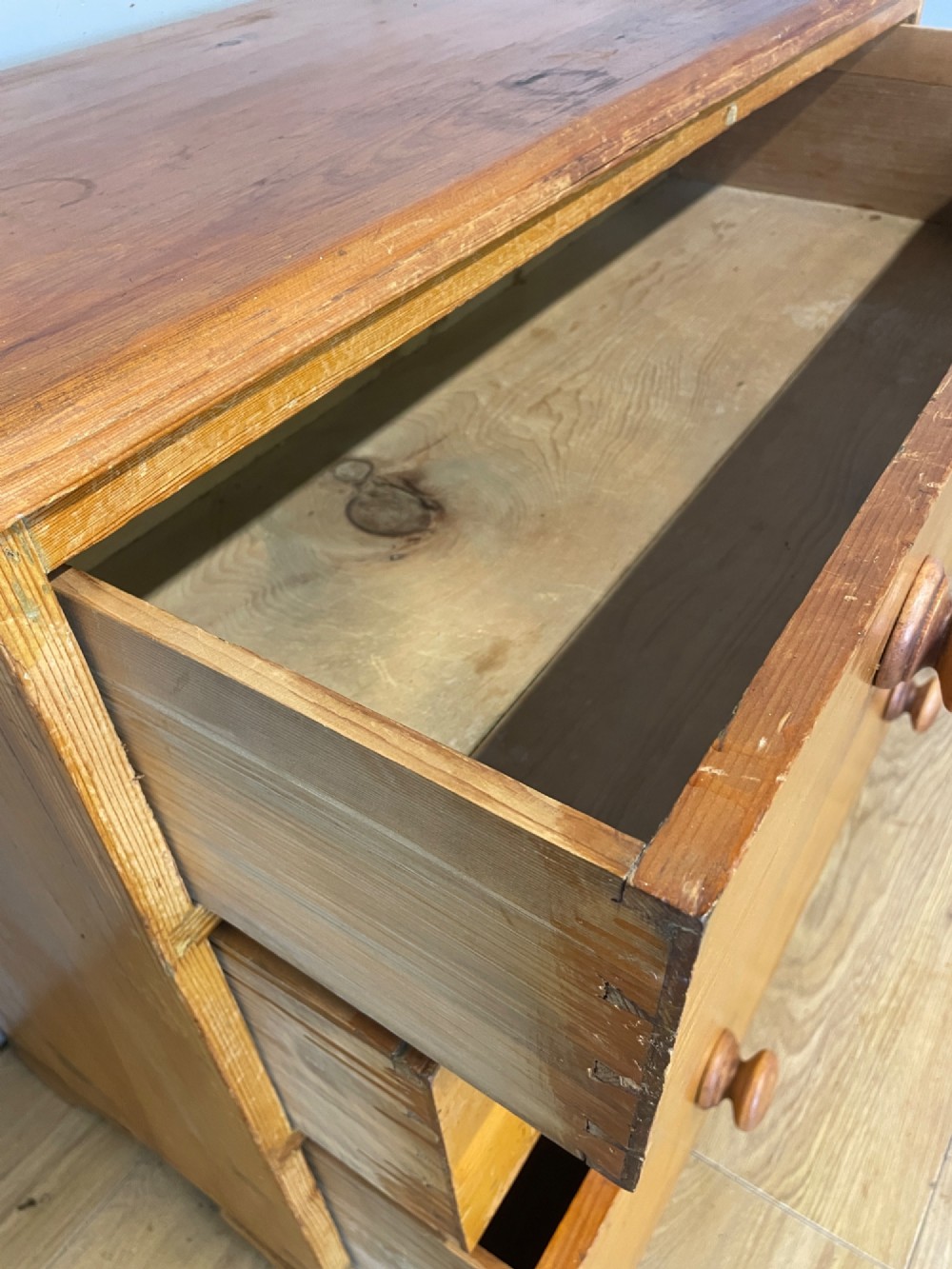 A nineteenth-century pine chest of drawers featuring three full-width drawers with turned wooden handles and bracket feet. View VI
