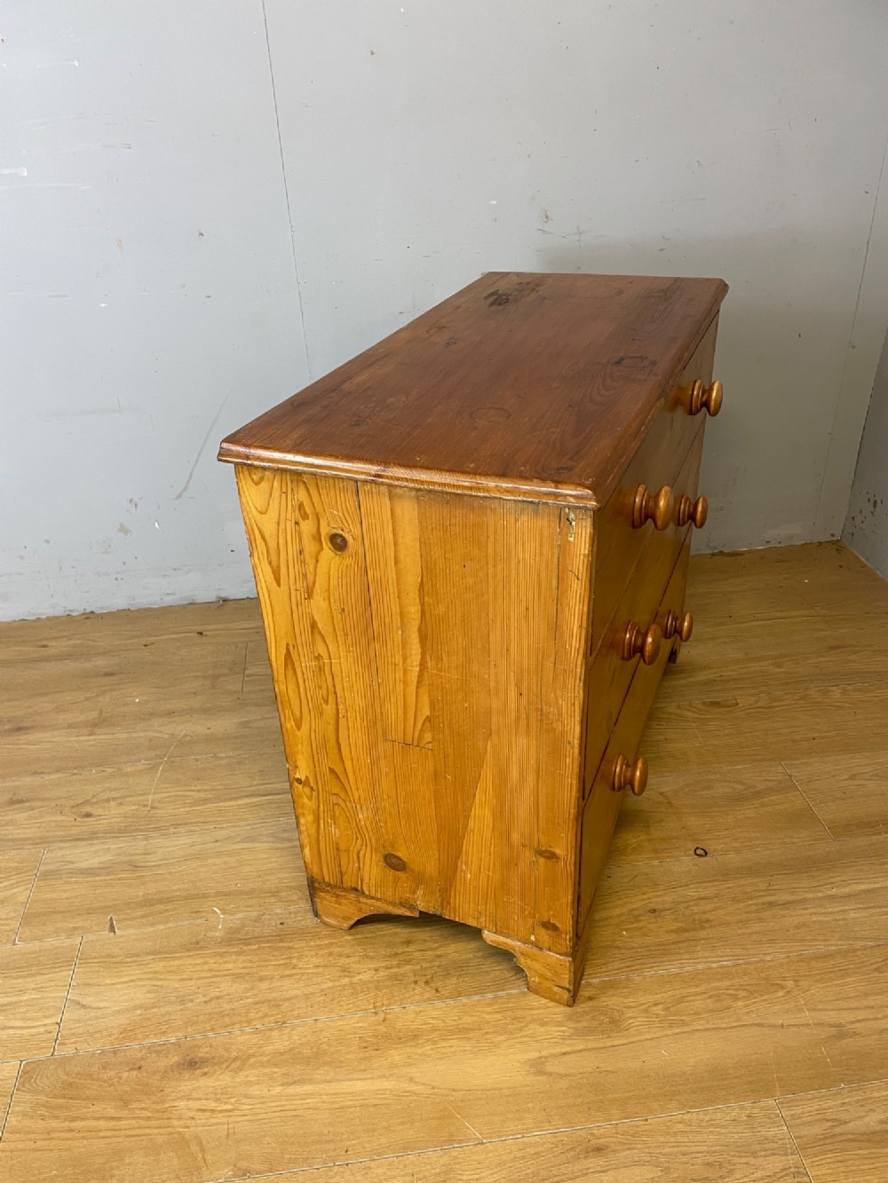 A nineteenth-century pine chest of drawers featuring three full-width drawers with turned wooden handles and bracket feet. View VII
