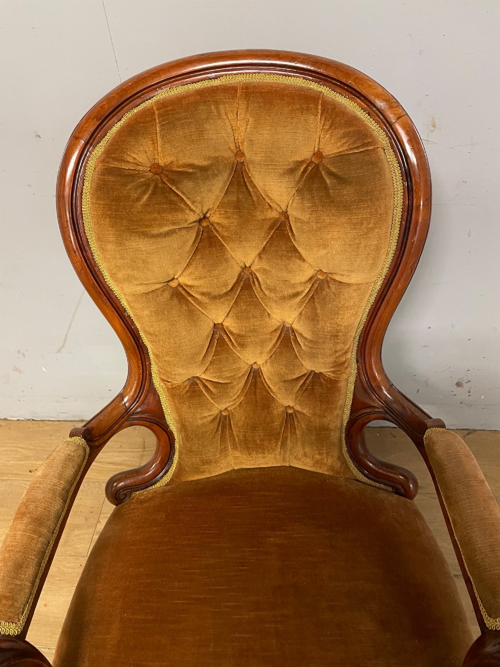 A Victorian walnut spoon back armchair featuring button-tufted mustard velvet upholstery, open carved armrests, and cabriole legs on brass castors. View IV