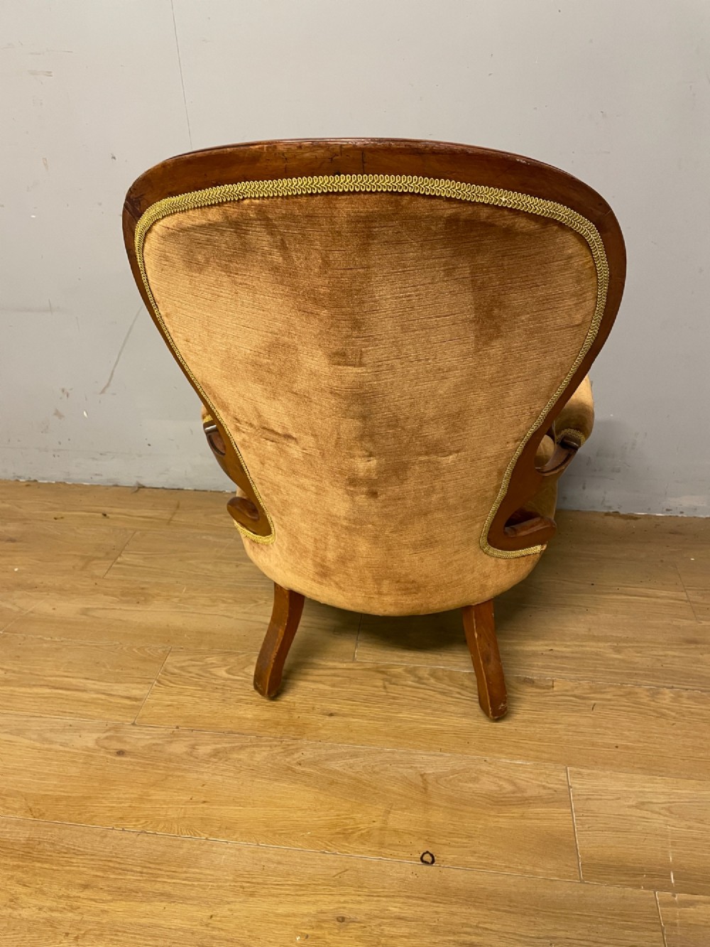 A Victorian walnut spoon back armchair featuring button-tufted mustard velvet upholstery, open carved armrests, and cabriole legs on brass castors. View VIII
