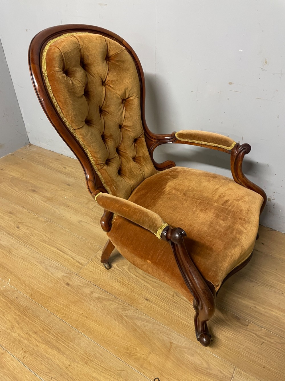 A Victorian walnut spoon back armchair featuring button-tufted mustard velvet upholstery, open carved armrests, and cabriole legs on brass castors. View IX