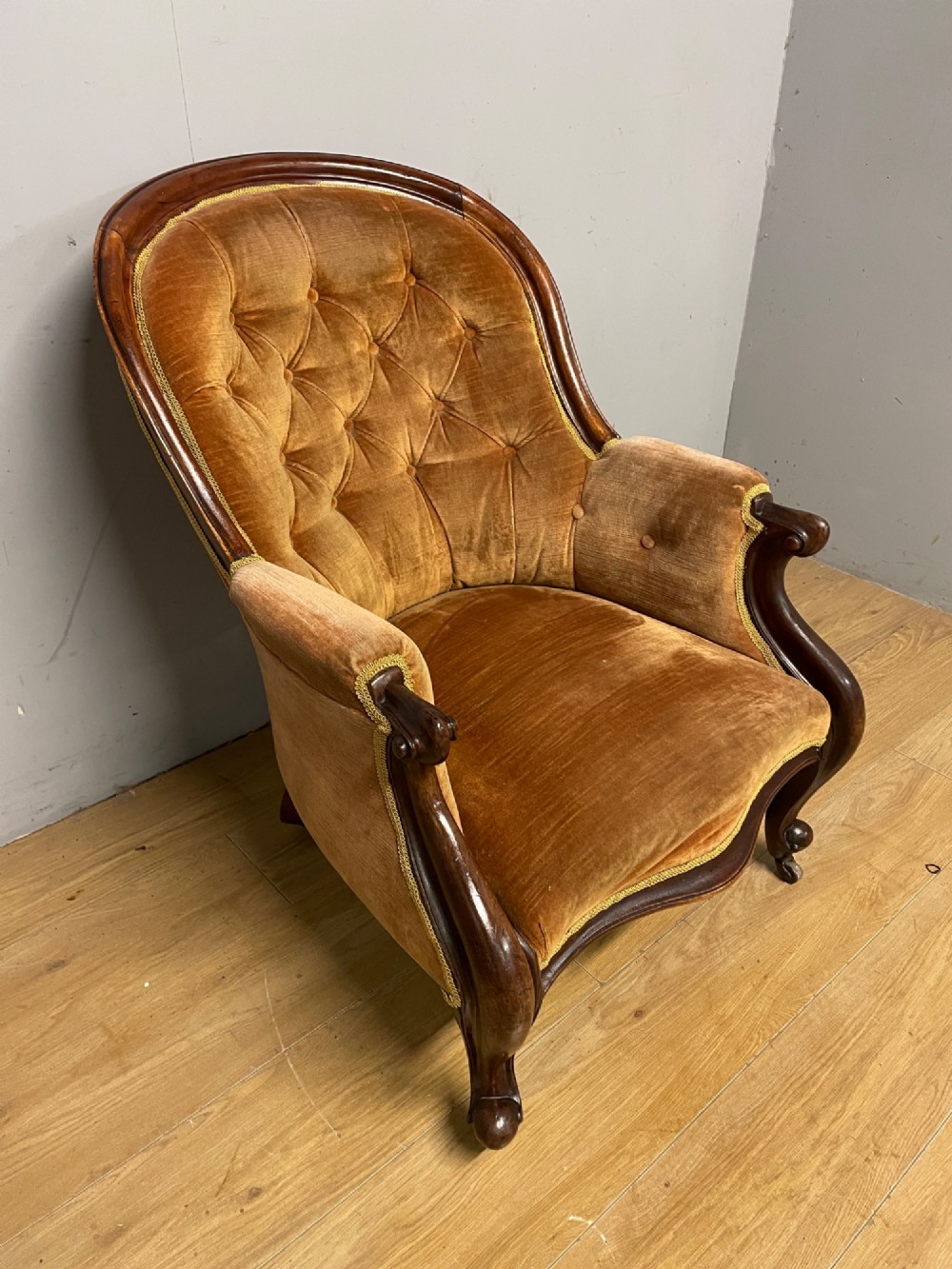 Victorian mahogany tub armchair upholstered in button-tufted amber velvet with curved front legs on brass castors. View II