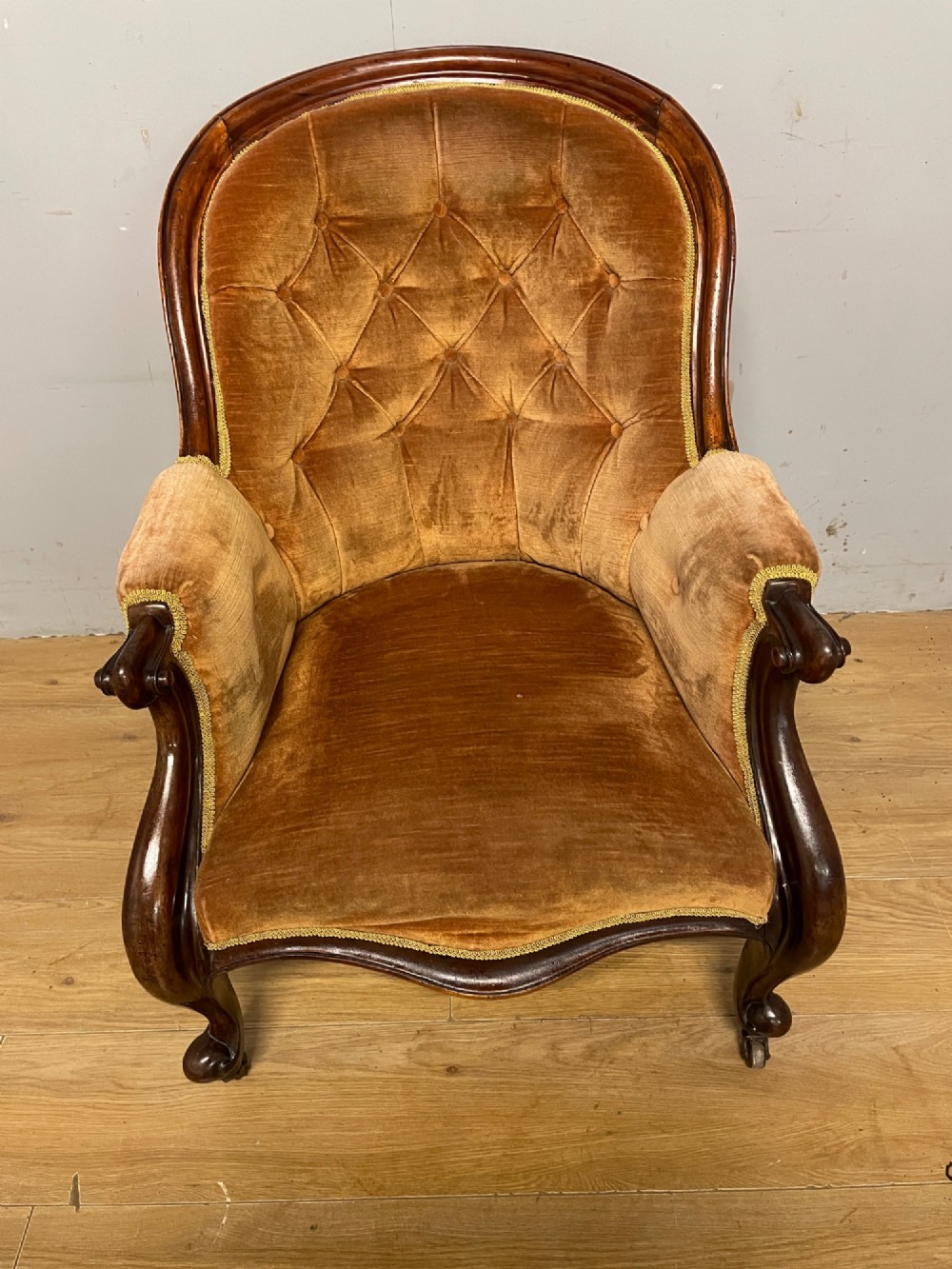 Victorian mahogany tub armchair upholstered in button-tufted amber velvet with curved front legs on brass castors. View III
