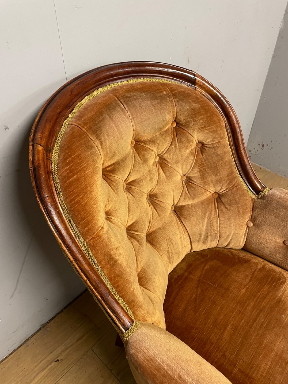 Victorian mahogany tub armchair upholstered in button-tufted amber velvet with curved front legs on brass castors. View V