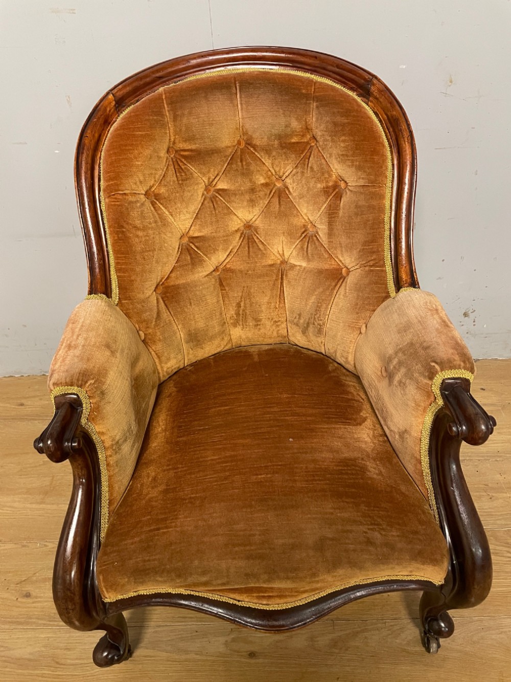 Victorian mahogany tub armchair upholstered in button-tufted amber velvet with curved front legs on brass castors. View VI