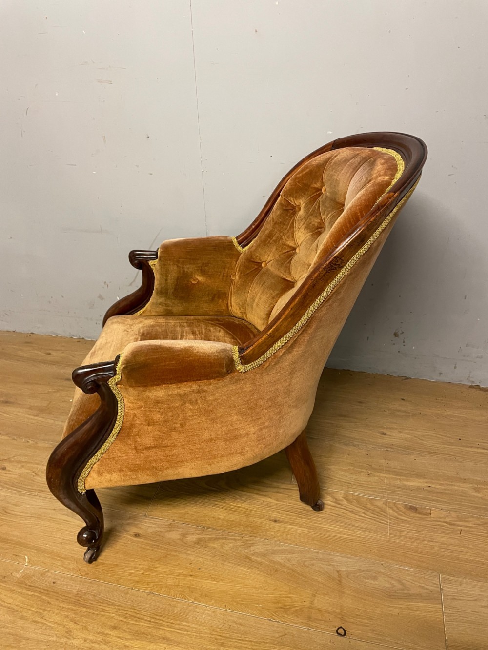 Victorian mahogany tub armchair upholstered in button-tufted amber velvet with curved front legs on brass castors. View VII