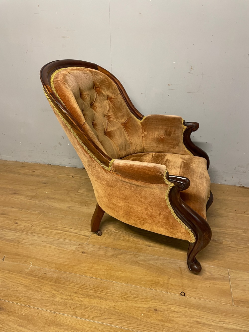 Victorian mahogany tub armchair upholstered in button-tufted amber velvet with curved front legs on brass castors. View IX