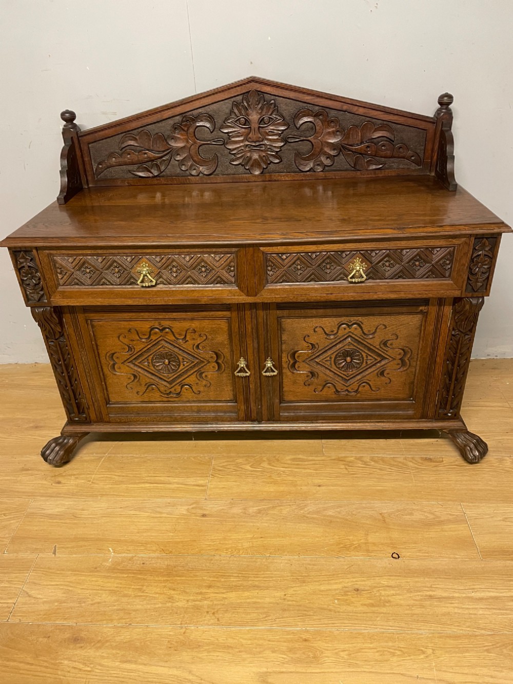 A nineteenth-century carved oak sideboard featuring a backboard gallery decorated with a Green Man motif, two geometric drawers, and two panelled cupboard doors. View II
