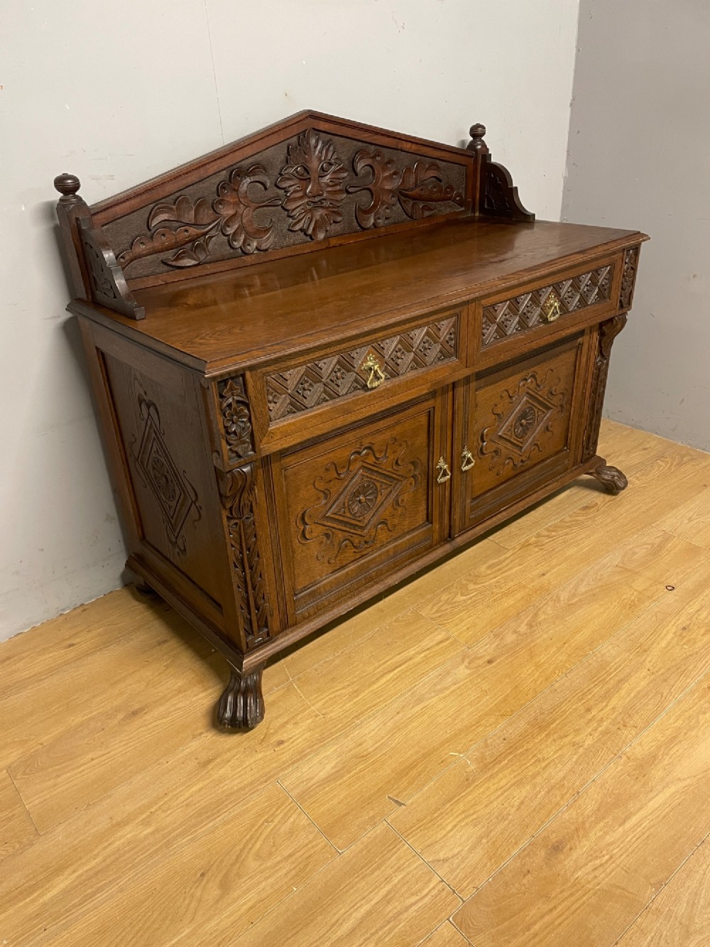 A nineteenth-century carved oak sideboard featuring a backboard gallery decorated with a Green Man motif, two geometric drawers, and two panelled cupboard doors. View III