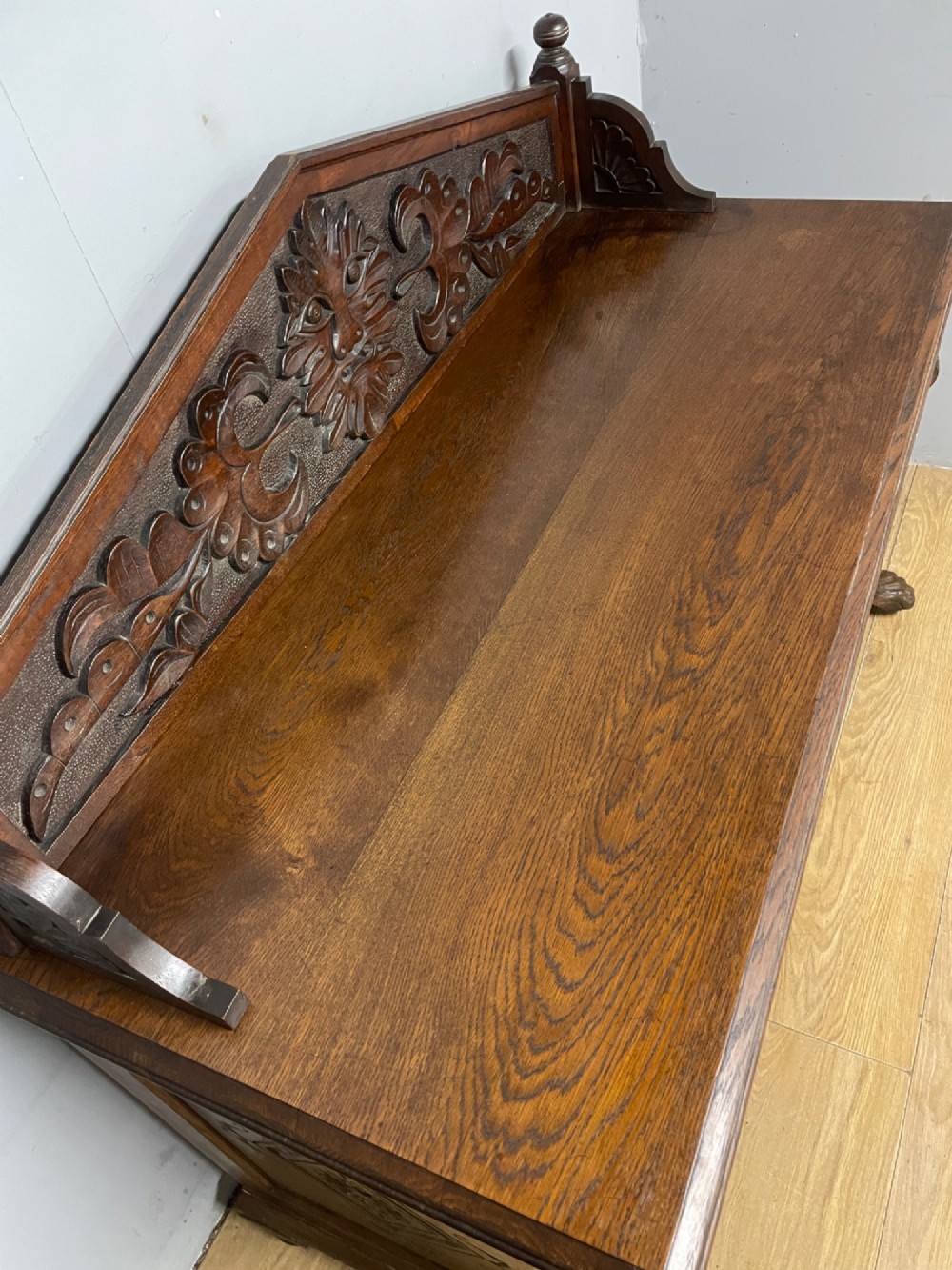 A nineteenth-century carved oak sideboard featuring a backboard gallery decorated with a Green Man motif, two geometric drawers, and two panelled cupboard doors. View V
