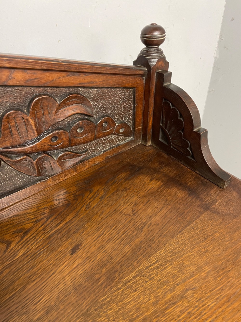 A nineteenth-century carved oak sideboard featuring a backboard gallery decorated with a Green Man motif, two geometric drawers, and two panelled cupboard doors. View XI