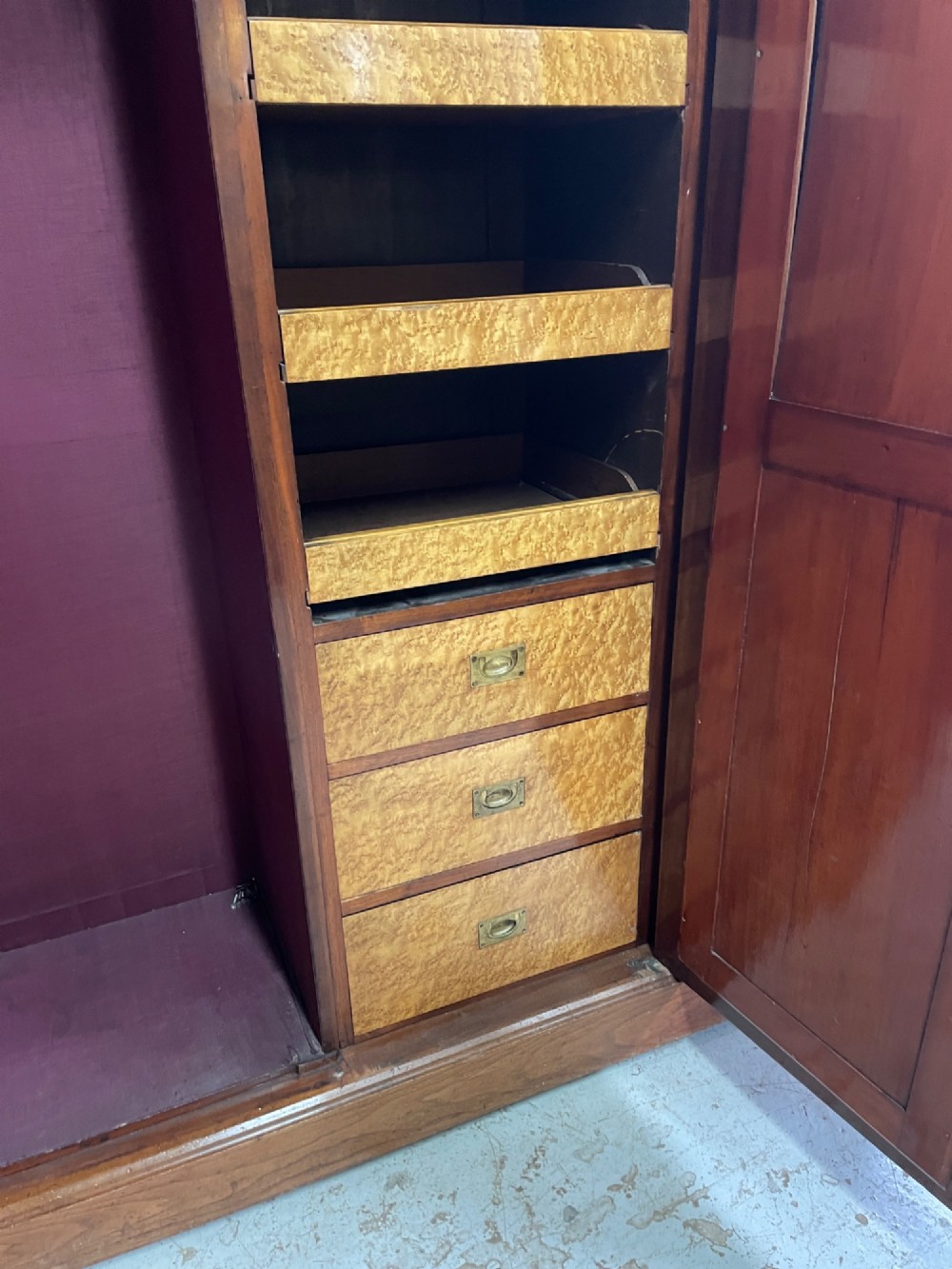 An Arts and Crafts walnut triple wardrobe featuring two outer timber doors with carved stylised flower panels and a central arched mirrored door with decorative brass hinges. View XI