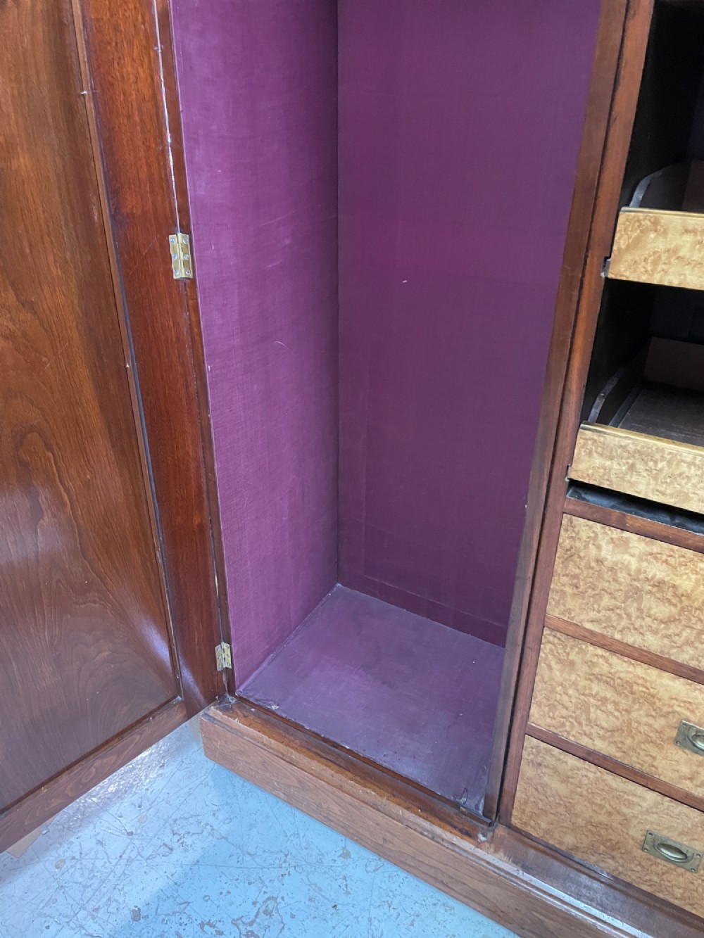 An Arts and Crafts walnut triple wardrobe featuring two outer timber doors with carved stylised flower panels and a central arched mirrored door with decorative brass hinges. View XIII