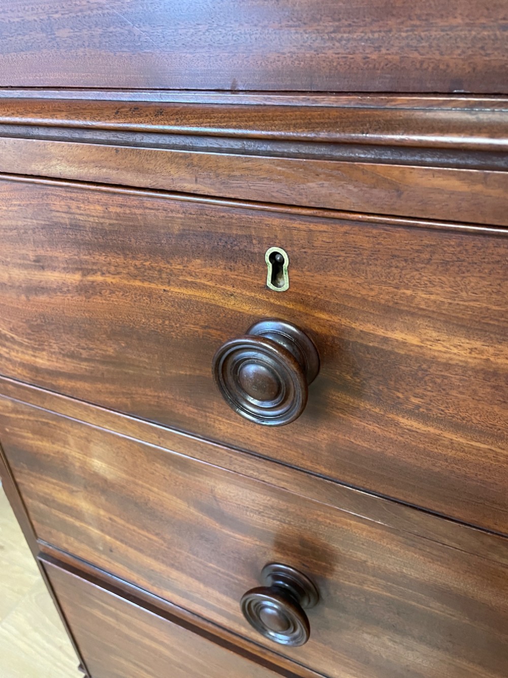 A two-part Regency flame mahogany linen press with twin panelled doors over four drawers with turned knobs. View VI