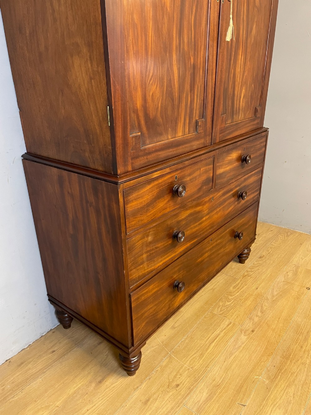 A two-part Regency flame mahogany linen press with twin panelled doors over four drawers with turned knobs. View VIII